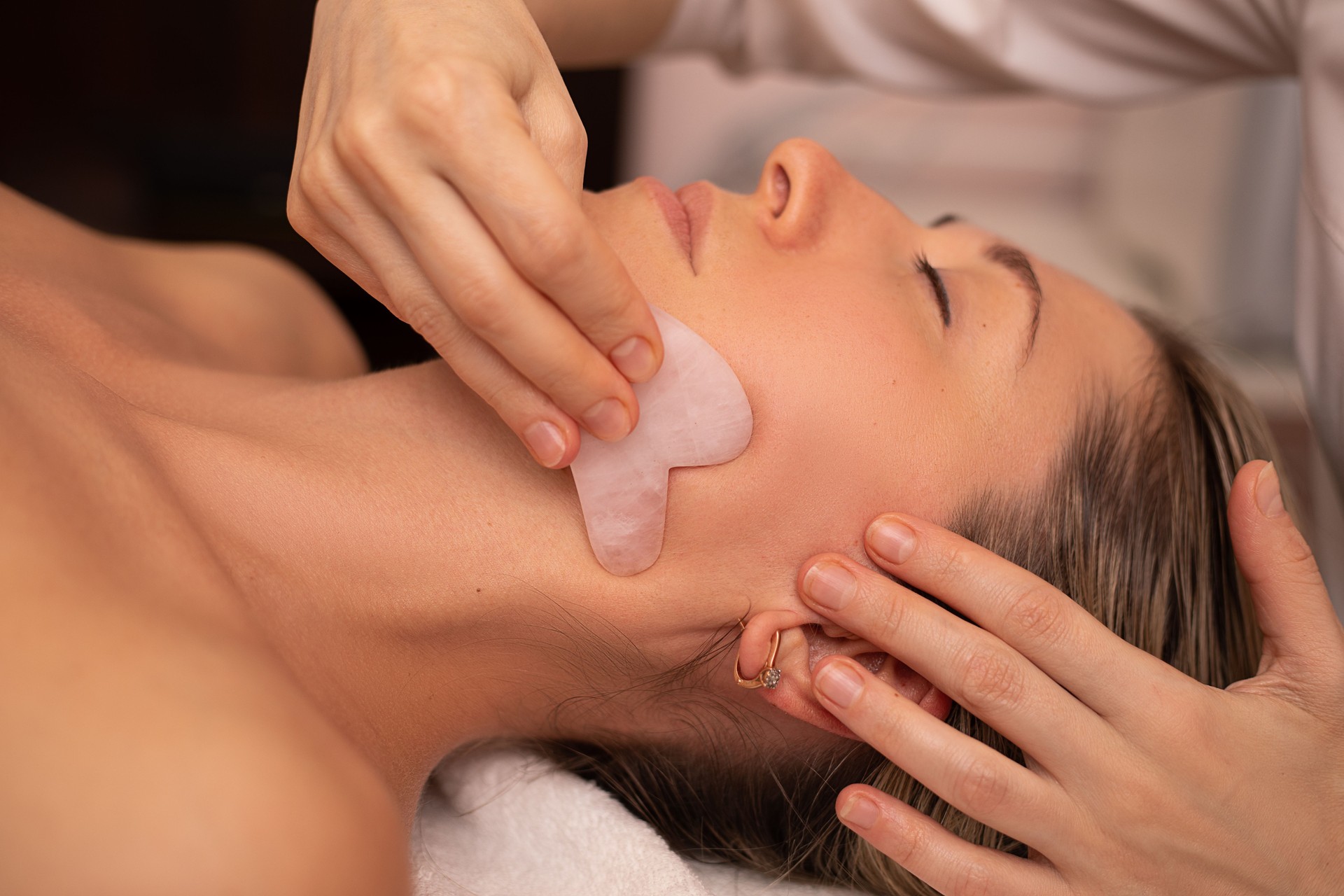 Young and beautiful woman during Chinese traditional massage - Gua Sha. Close-up photo. Beauty treatment in SPA salon. Anti-aging skin care